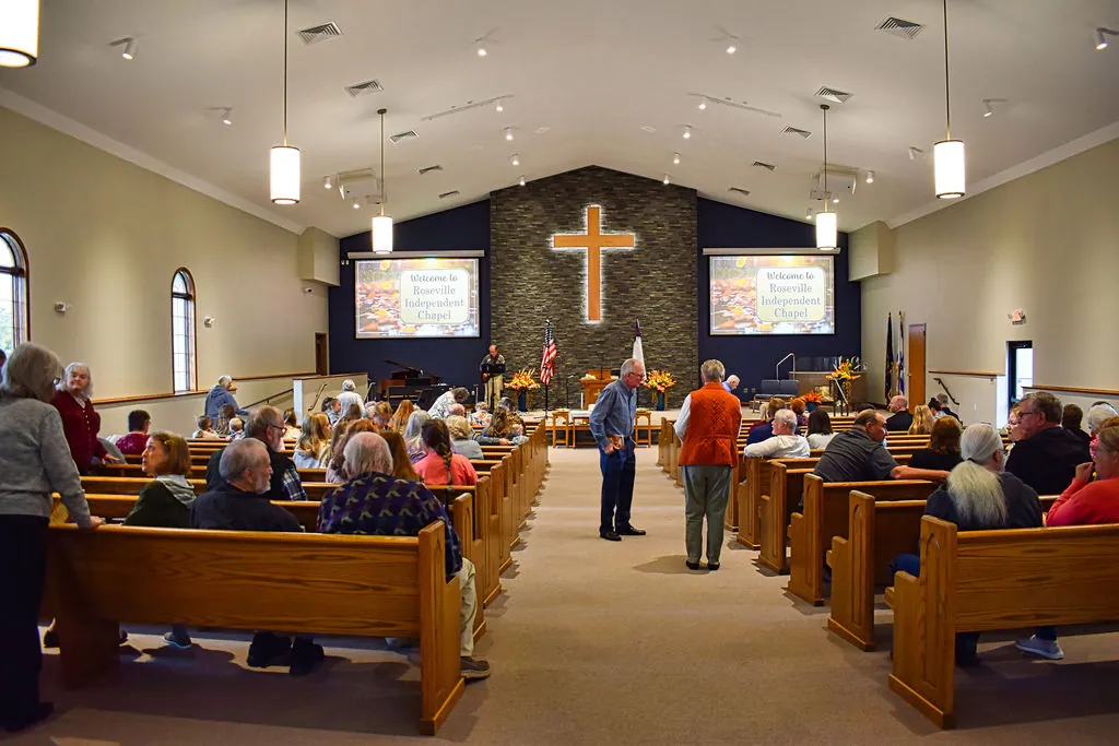 Neighbors catching up in the aisle and pews of the sanctuary before worship, Welcome to Roseville Independent Chapel on both screens